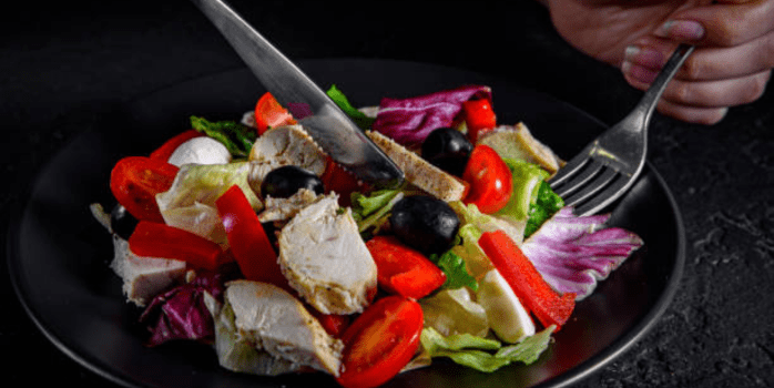 A colorful array of ingredients for the Delicious Chicken Tahini Salad Dish, including diced chicken, fresh vegetables, tahini, and spices, beautifully arranged on a wooden cutting board.